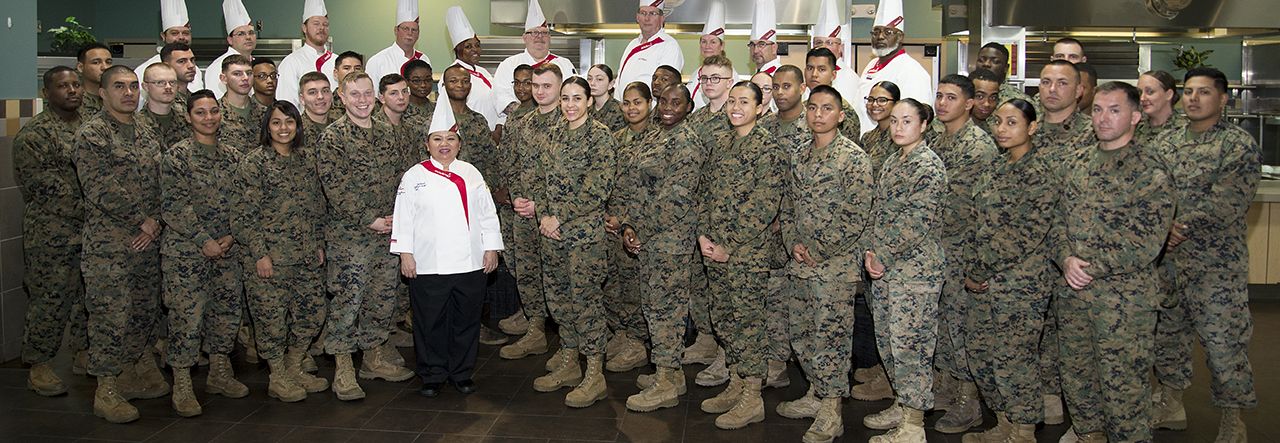 Group of male and female soldiers and military chefs posing together for a group photo